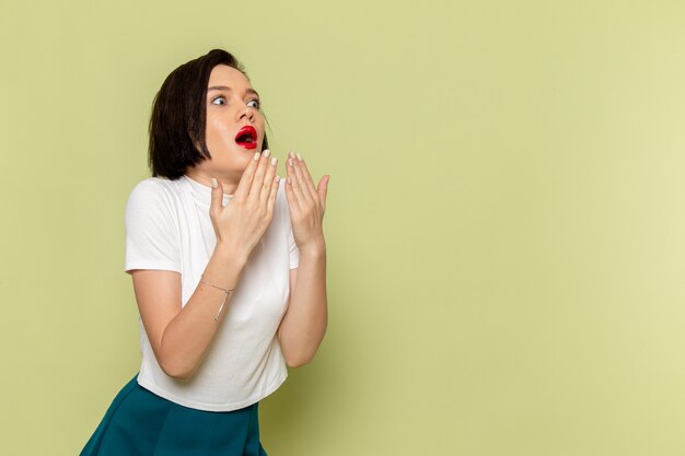 woman in white blouse and green skirt posign with shocked expression 