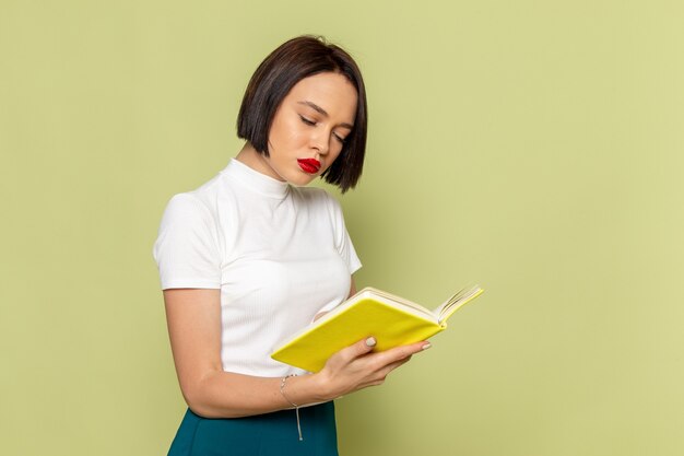 woman in white blouse and green skirt reading a book