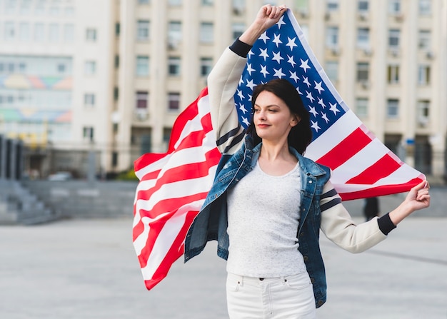 Foto gratuita donna in abiti bianchi con bandiera americana sulla strada