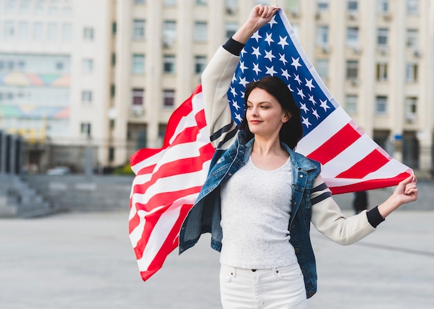 Женщина в белых одеждах с американским флагом на улице
