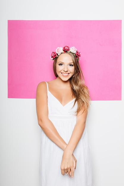 Woman in white cotton dress with flowers in hair smiling