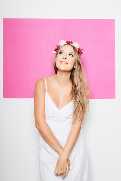 Woman in white cotton dress with flowers in hair smiling