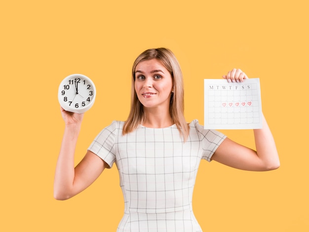 Free photo woman in white dress shows clock and calendar