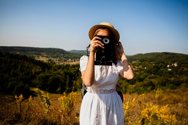 カメラの写真を撮る白いドレスを着た女性