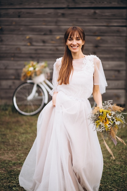 Woman in white dress with bicycle by the wooden wall