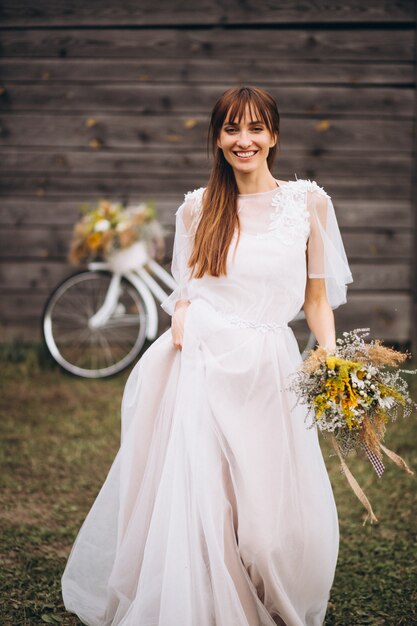 木製の壁の自転車と白いドレスの女