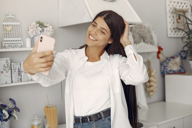 Rheキッチンに立って、selfieを作る白いシャツの女性
