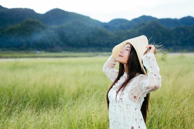 山のある美しい草原で手に草を持っている女性。