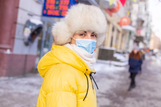 Woman in winter clothes on a cold day waiting for a bus at a bus stop