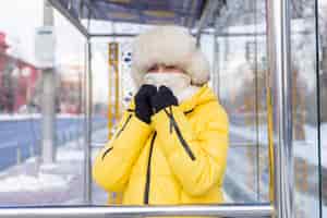 Foto gratuita donna in abiti invernali in una fredda giornata in attesa di un autobus a una fermata dell'autobus