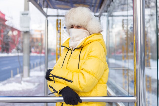 バス停でバスを待っている寒い日に冬服を着た女性