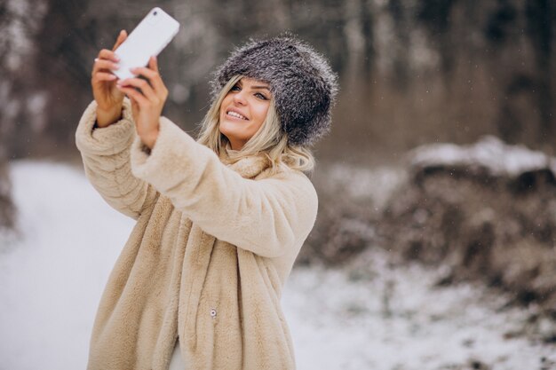 Woman in winter coat walking in park full of snow talking on the phone