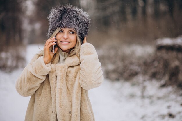 전화 통화하는 눈이 가득한 공원에서 산책하는 겨울 코트에 여자