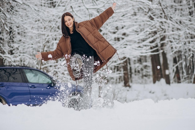 Woman in winter forest by her car