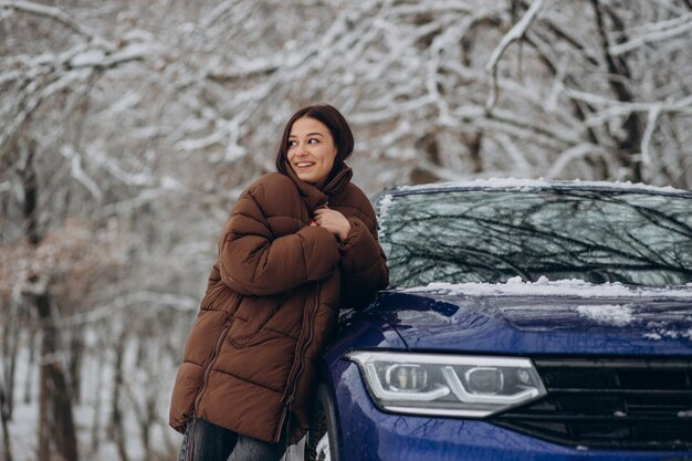 Woman in winter forest by her car