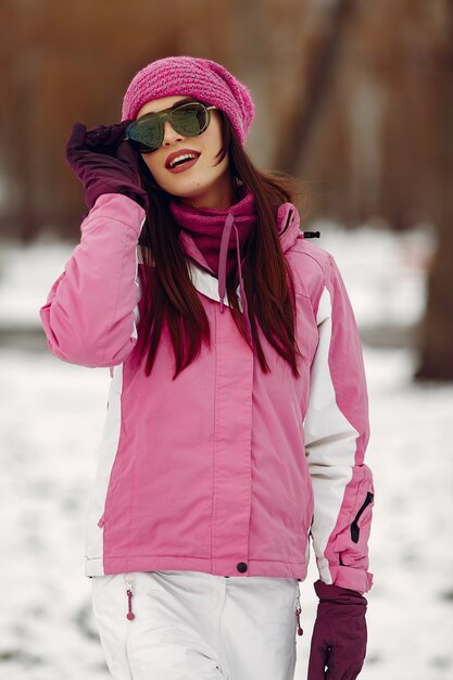 Woman in a winter park. Lady in pink sportsuit. Girl in a sunglasses.