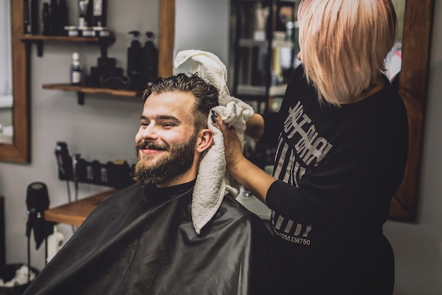 Woman wiping head of customer with towel