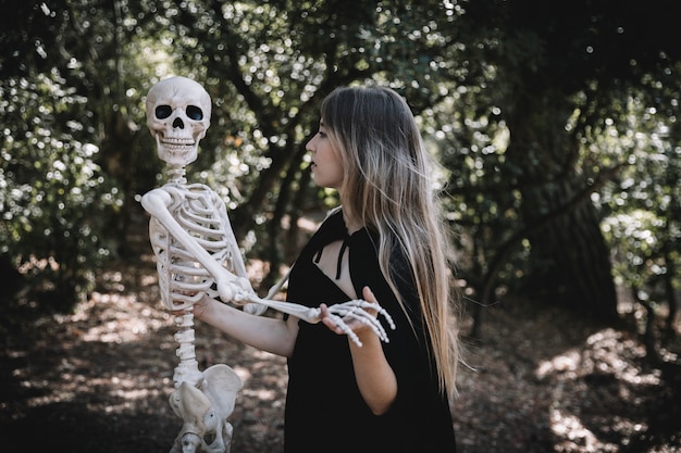 Woman in witch costume holding skeleton