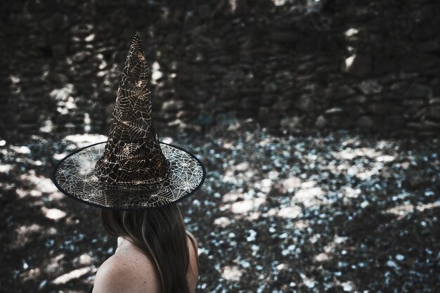 森の中に立つ魔女帽子の女