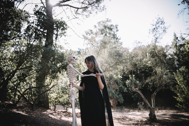 Woman in witch suit holding skeleton