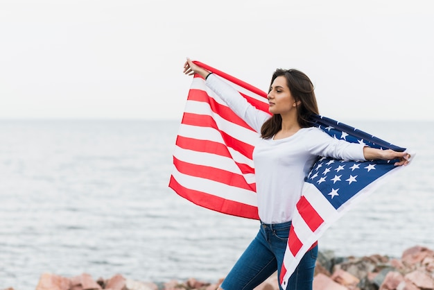 海でアメリカの旗を持つ女性