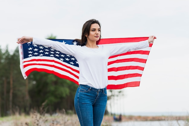 海でアメリカの旗を持つ女性