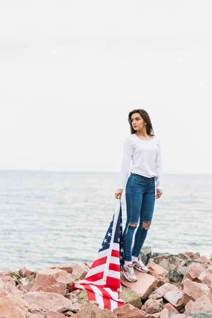 海でアメリカの旗を持つ女性