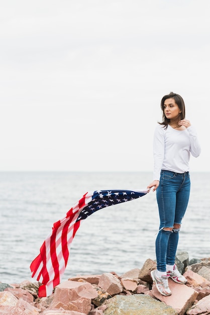 海でアメリカの旗を持つ女性