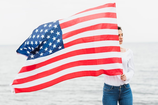 海でアメリカの旗を持つ女性