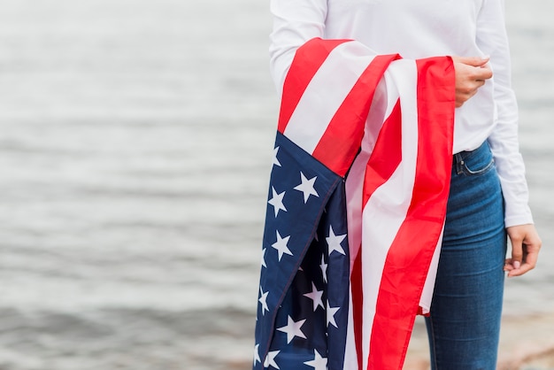 海でアメリカの旗を持つ女性