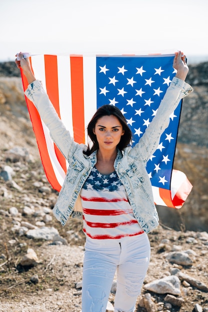 カメラを見てアメリカの国旗を持つ女性