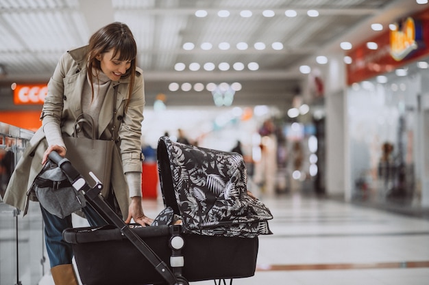 Free photo woman with baby carriage in shopping mall