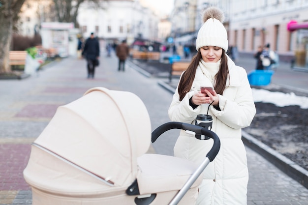 Woman with baby in carriage using phone