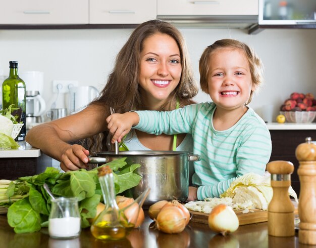 Woman with baby cooking at kitchen