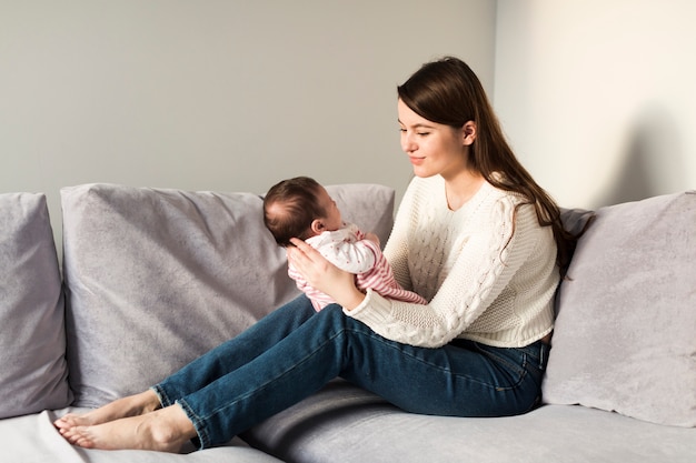 Woman with baby sitting on sofa