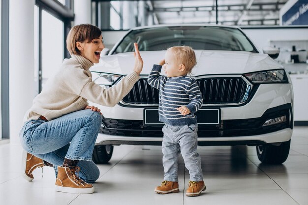 Woman with baby son choosing a car in a car salon