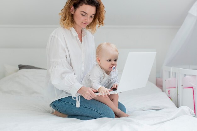 Woman with baby working in bed