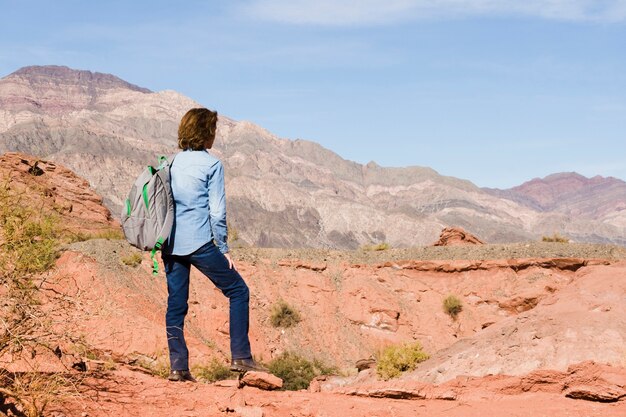 женщина с рюкзаком наслаждается горным пейзажем