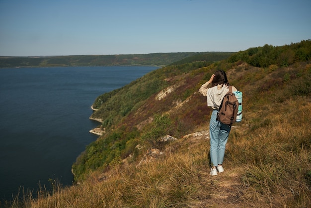 Free photo woman with backpack walking along high green hill