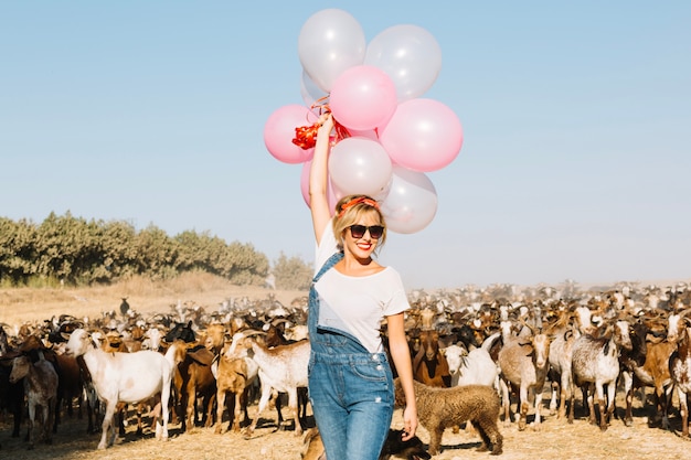 Foto gratuita donna con palloncini camminando vicino a capre