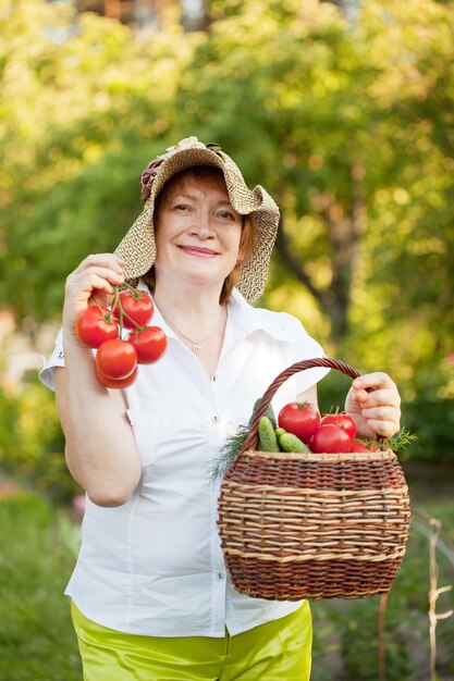 収穫した野菜のバスケットを持つ女性