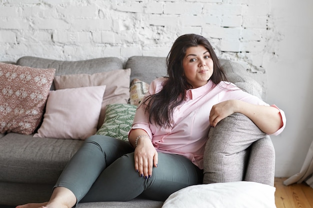 A woman with beautiful body is posing on the couch