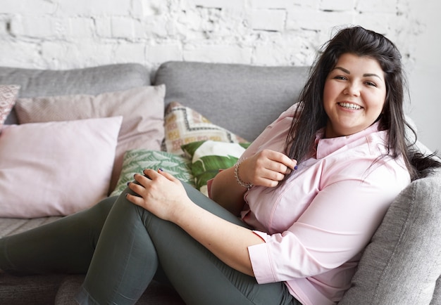 A woman with beautiful body is posing on the couch