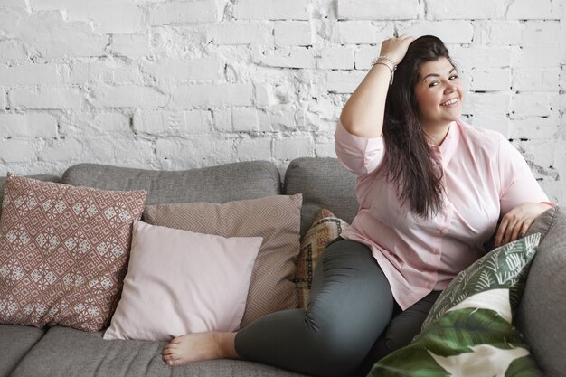 A woman with beautiful body is posing on the couch