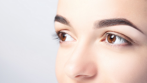 Woman with beautiful eyebrows close-up on a light background with copy space