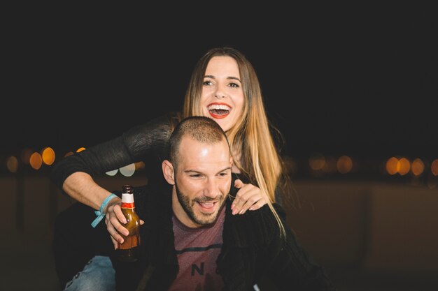 Woman with beer riding on back of man
