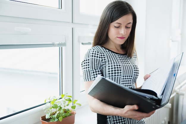 Foto gratuita donna con grande cartella posa in ufficio