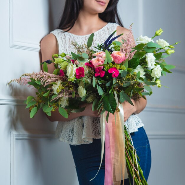 チュールリボンと大きな混合花束を持つ女性。