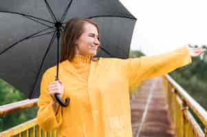 Бесплатное фото Женщина с черным зонтом поднимает руку