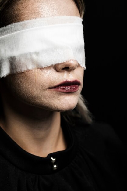 Woman with blindfold on black background